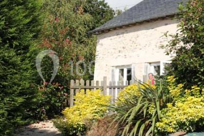 Lit double avec une couette blanche dans une chambre mansardée aux murs en pierre et plafond en bois.