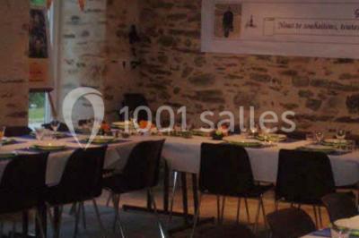 Lit double avec une couette blanche dans une chambre mansardée aux murs en pierre et plafond en bois.