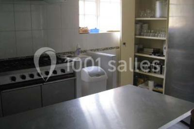 Lit double avec une couette blanche dans une chambre mansardée aux murs en pierre et plafond en bois.