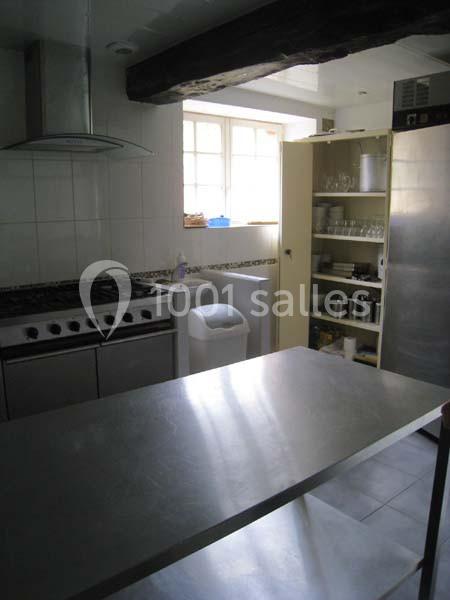 Cuisine équipée avec plan de travail en inox, cuisinière à gaz, étagères ouvertes et fenêtre laissant entrer la lumière…