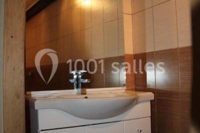 Lit double avec une couette blanche dans une chambre mansardée aux murs en pierre et plafond en bois.