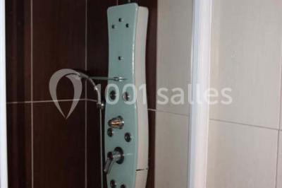 Lit double avec une couette blanche dans une chambre mansardée aux murs en pierre et plafond en bois.