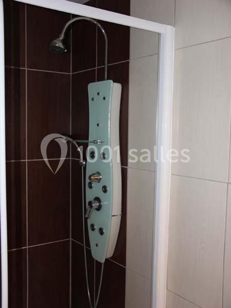 Colonne de douche moderne avec pommeau, jets intégrés et robinetterie, installée dans une cabine carrelée.