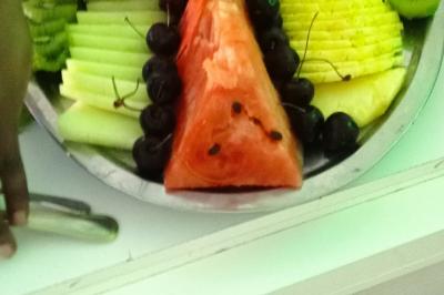 Plateaux de fruits frais composés de bananes, ananas, raisins, fraises, oranges et pastèques, décorés avec des couteaux.