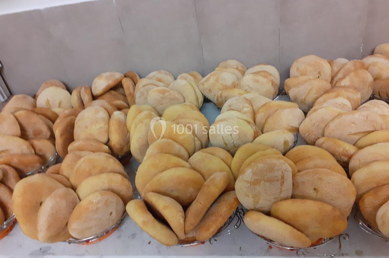 Des pains ronds dorés alignés sur des plateaux dans un environnement de cuisine ou de boulangerie.