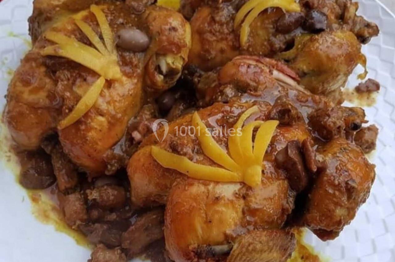 Poulet rôti garni de citrons confits et olives, présenté sur une assiette blanche.