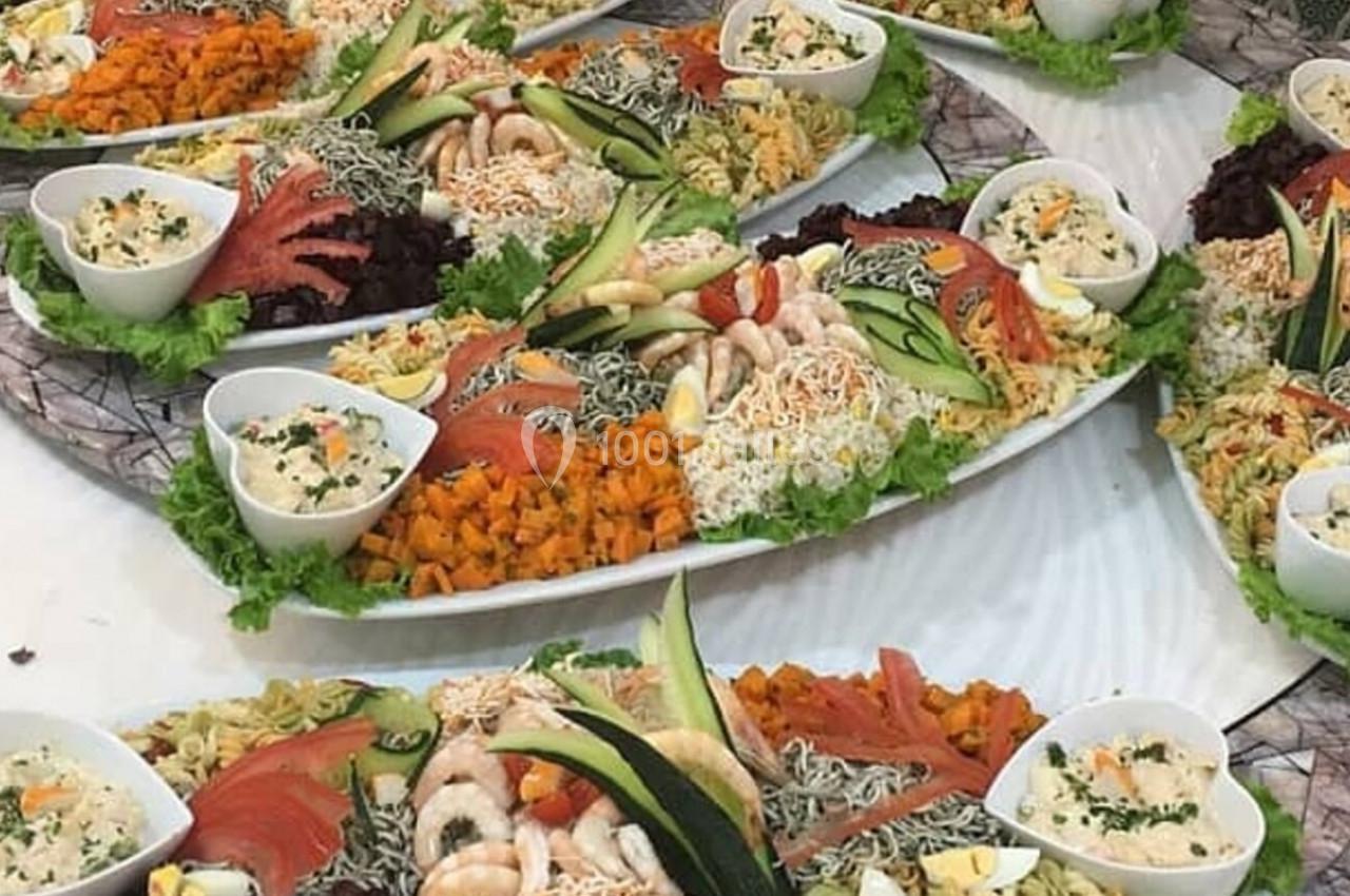 Plats garnis de salades variées, légumes, pâtes, crevettes et sauces, présentés sur de grands plateaux ovales.