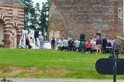 Château illuminé de nuit avec des murs en pierre, entouré d'arbres et d'une chaîne métallique au premier plan.