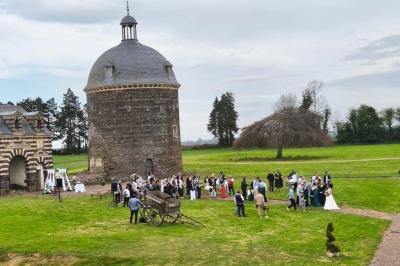 Château illuminé de nuit avec des murs en pierre, entouré d'arbres et d'une chaîne métallique au premier plan.
