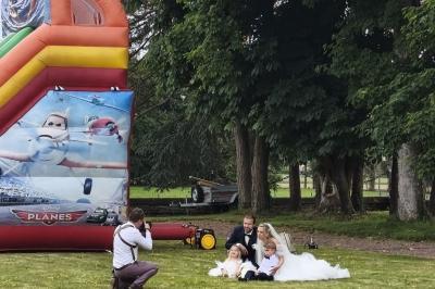 Château illuminé de nuit avec des murs en pierre, entouré d'arbres et d'une chaîne métallique au premier plan.