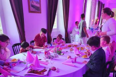 Château illuminé de nuit avec des murs en pierre, entouré d'arbres et d'une chaîne métallique au premier plan.