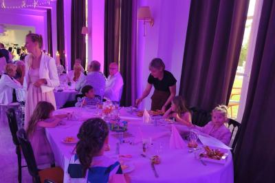 Château illuminé de nuit avec des murs en pierre, entouré d'arbres et d'une chaîne métallique au premier plan.