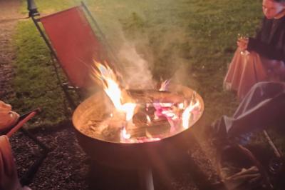 Château illuminé de nuit avec des murs en pierre, entouré d'arbres et d'une chaîne métallique au premier plan.