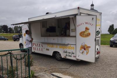 Château illuminé de nuit avec des murs en pierre, entouré d'arbres et d'une chaîne métallique au premier plan.