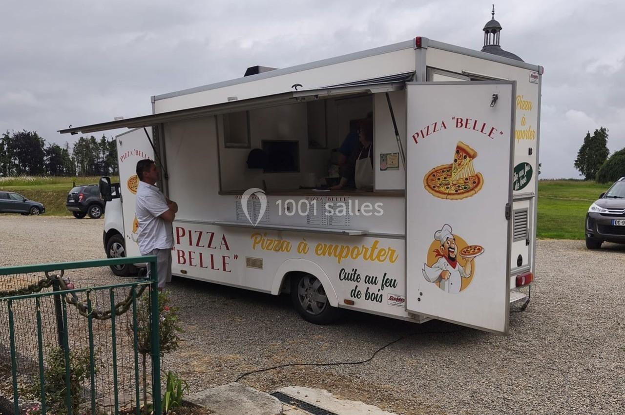 Camion de pizza stationné en extérieur, avec un homme commandant au comptoir.