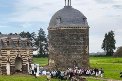Château illuminé de nuit avec des murs en pierre, entouré d'arbres et d'une chaîne métallique au premier plan.