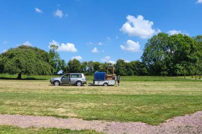 Château illuminé de nuit avec des murs en pierre, entouré d'arbres et d'une chaîne métallique au premier plan.