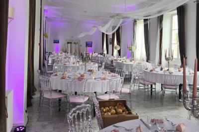 Château illuminé de nuit avec des murs en pierre, entouré d'arbres et d'une chaîne métallique au premier plan.