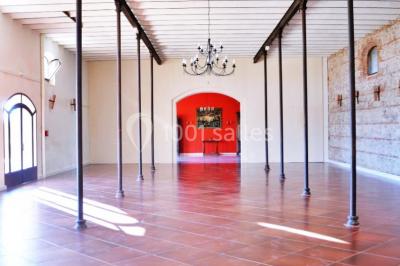Table et chaises en fer forgé avec coussins bleus sur une terrasse ensoleillée devant un bâtiment en briques et grandes…
