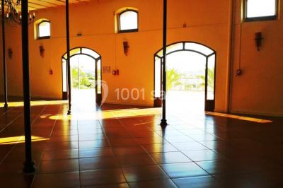 Table et chaises en fer forgé avec coussins bleus sur une terrasse ensoleillée devant un bâtiment en briques et grandes…