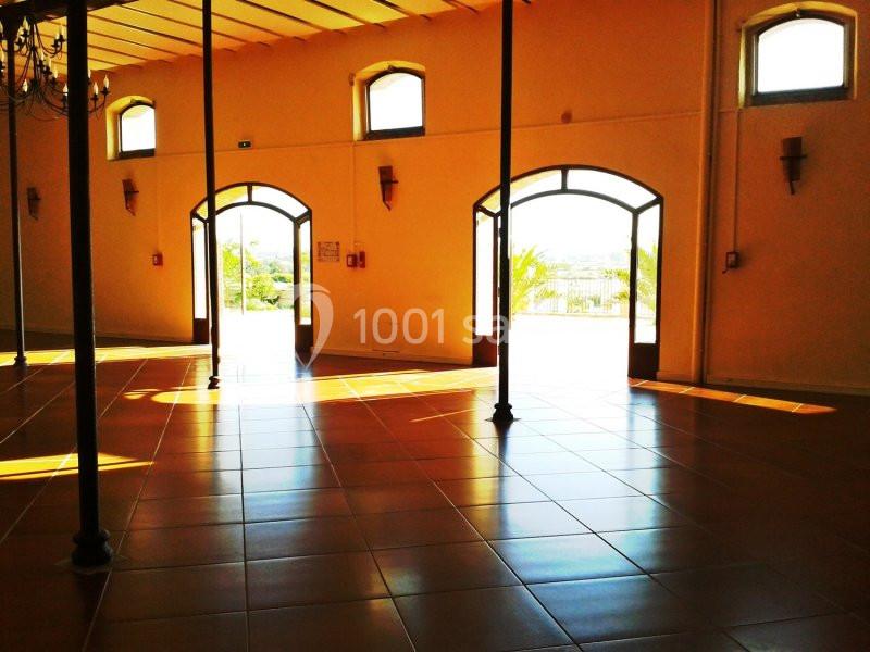 Salle lumineuse avec sol en carrelage, grandes portes vitrées ouvertes sur un extérieur ensoleillé.