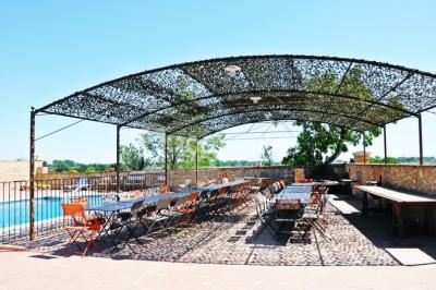 Table et chaises en fer forgé avec coussins bleus sur une terrasse ensoleillée devant un bâtiment en briques et grandes…