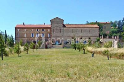Table et chaises en fer forgé avec coussins bleus sur une terrasse ensoleillée devant un bâtiment en briques et grandes…