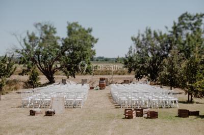 Table et chaises en fer forgé avec coussins bleus sur une terrasse ensoleillée devant un bâtiment en briques et grandes…