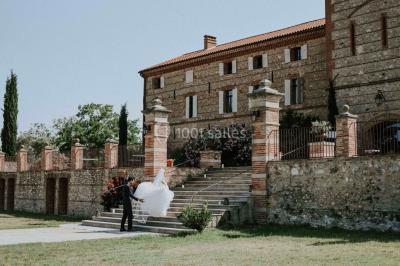 Table et chaises en fer forgé avec coussins bleus sur une terrasse ensoleillée devant un bâtiment en briques et grandes…