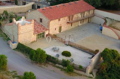 Table et chaises en fer forgé avec coussins bleus sur une terrasse ensoleillée devant un bâtiment en briques et grandes…