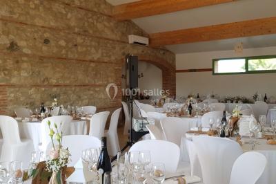 Table et chaises en fer forgé avec coussins bleus sur une terrasse ensoleillée devant un bâtiment en briques et grandes…