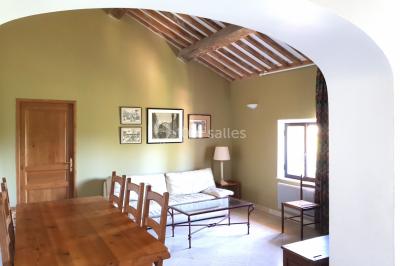 Table et chaises en fer forgé avec coussins bleus sur une terrasse ensoleillée devant un bâtiment en briques et grandes…