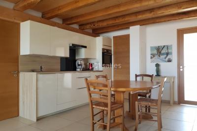 Table et chaises en fer forgé avec coussins bleus sur une terrasse ensoleillée devant un bâtiment en briques et grandes…
