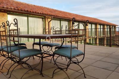 Table et chaises en fer forgé avec coussins bleus sur une terrasse ensoleillée devant un bâtiment en briques et grandes…