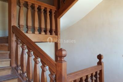 Table et chaises en fer forgé avec coussins bleus sur une terrasse ensoleillée devant un bâtiment en briques et grandes…