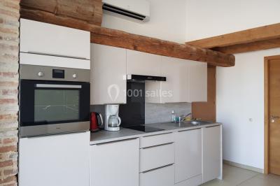 Table et chaises en fer forgé avec coussins bleus sur une terrasse ensoleillée devant un bâtiment en briques et grandes…