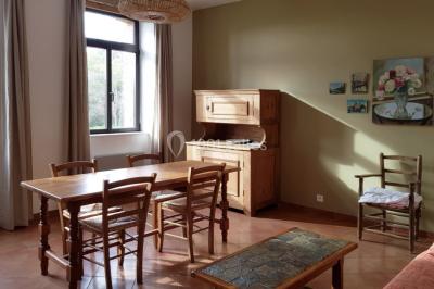 Table et chaises en fer forgé avec coussins bleus sur une terrasse ensoleillée devant un bâtiment en briques et grandes…