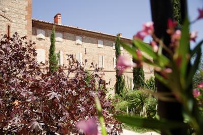 Table et chaises en fer forgé avec coussins bleus sur une terrasse ensoleillée devant un bâtiment en briques et grandes…