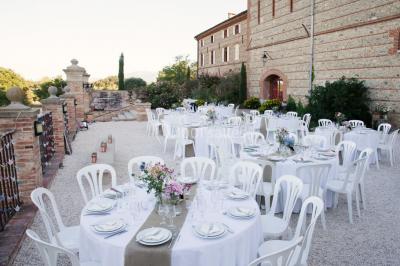 Table et chaises en fer forgé avec coussins bleus sur une terrasse ensoleillée devant un bâtiment en briques et grandes…