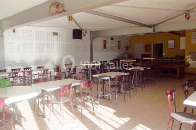 Bar avec comptoir en bois, tabourets, table ronde sur un tonneau, éclairage coloré et décoration murale.