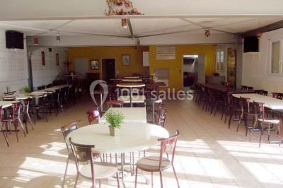 Bar avec comptoir en bois, tabourets, table ronde sur un tonneau, éclairage coloré et décoration murale.