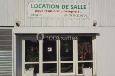 Bar avec comptoir en bois, tabourets, table ronde sur un tonneau, éclairage coloré et décoration murale.