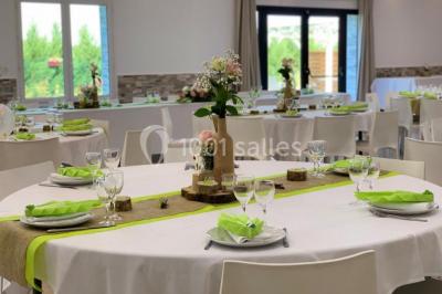 Bâtiment à façade rouge et blanche avec une pergola blanche et un banc en pierre dans un jardin verdoyant.