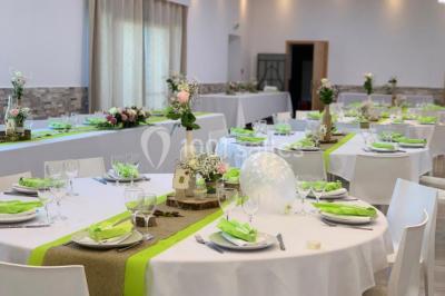 Bâtiment à façade rouge et blanche avec une pergola blanche et un banc en pierre dans un jardin verdoyant.