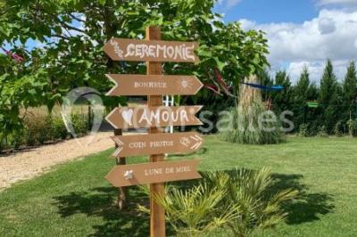 Bâtiment à façade rouge et blanche avec une pergola blanche et un banc en pierre dans un jardin verdoyant.