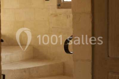 Un bâtiment en pierre avec un toit en tuiles rouges, entouré de jardins fleuris, accueille un groupe de personnes.