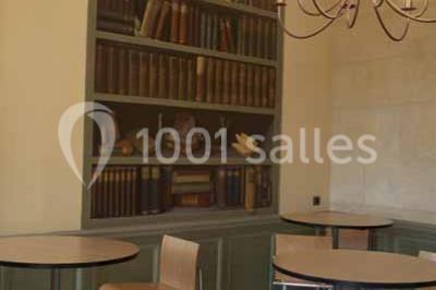 Un bâtiment en pierre avec un toit en tuiles rouges, entouré de jardins fleuris, accueille un groupe de personnes.