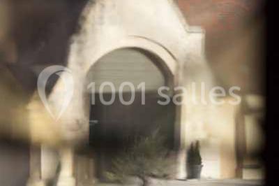Un bâtiment en pierre avec un toit en tuiles rouges, entouré de jardins fleuris, accueille un groupe de personnes.