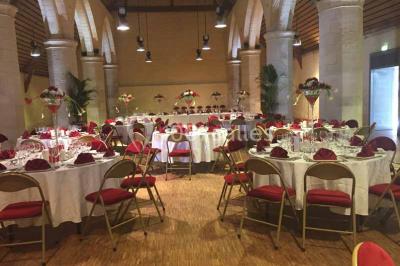 Un bâtiment en pierre avec un toit en tuiles rouges, entouré de jardins fleuris, accueille un groupe de personnes.