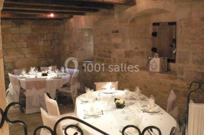 Un bâtiment en pierre avec un toit en tuiles rouges, entouré de jardins fleuris, accueille un groupe de personnes.